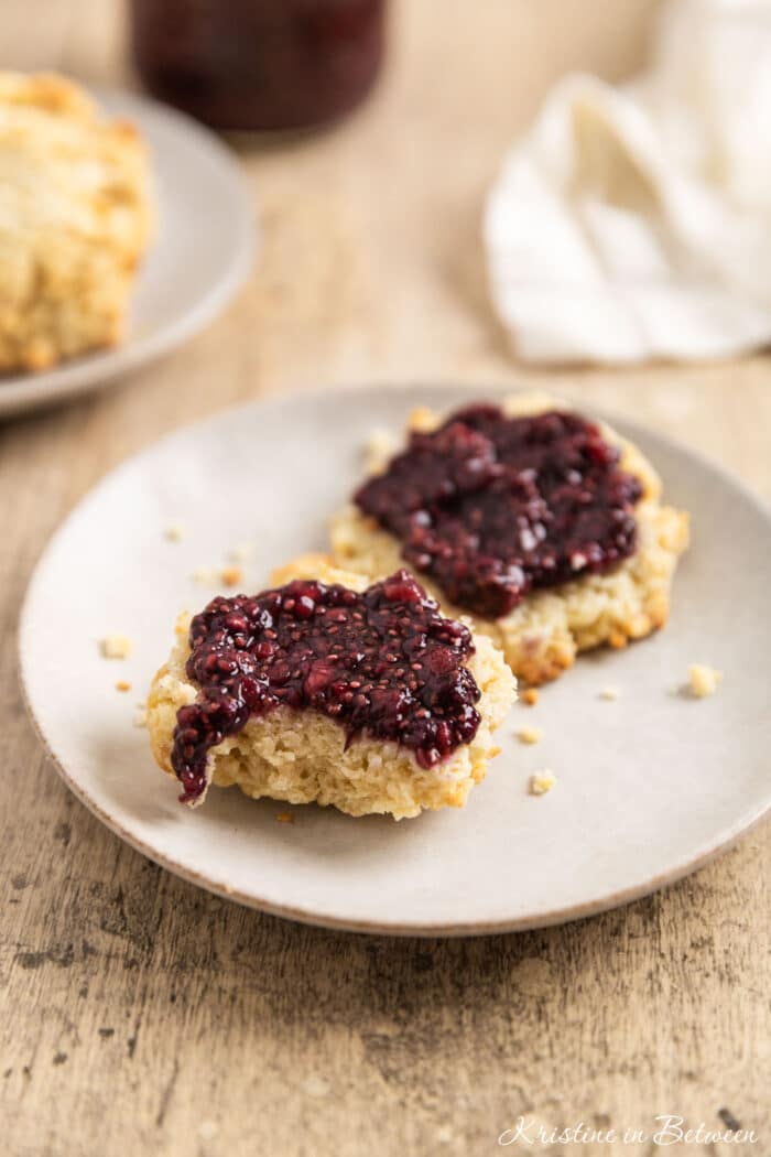 A biscuit cut in half with raspberry chia seed jam spread over the top.