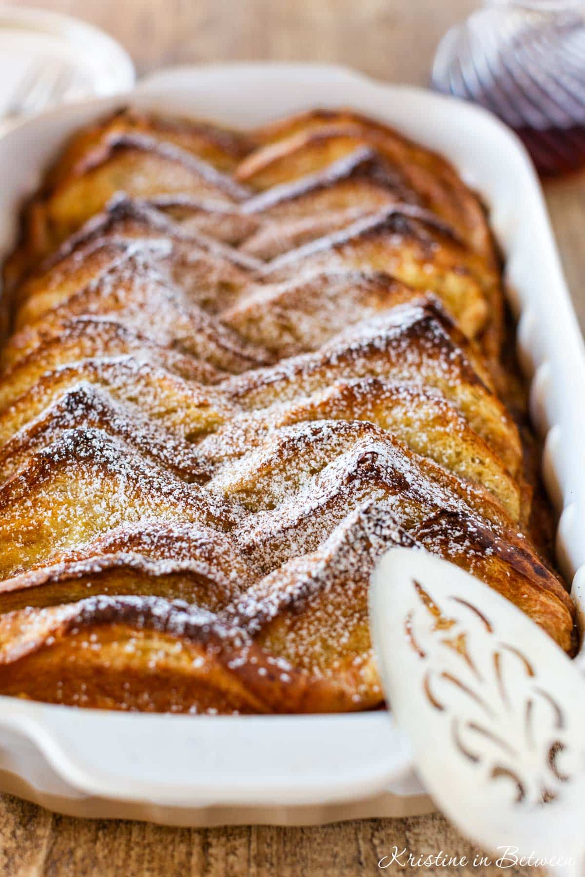 A pan of baked French toast with powdered sugar sprinkled on top.