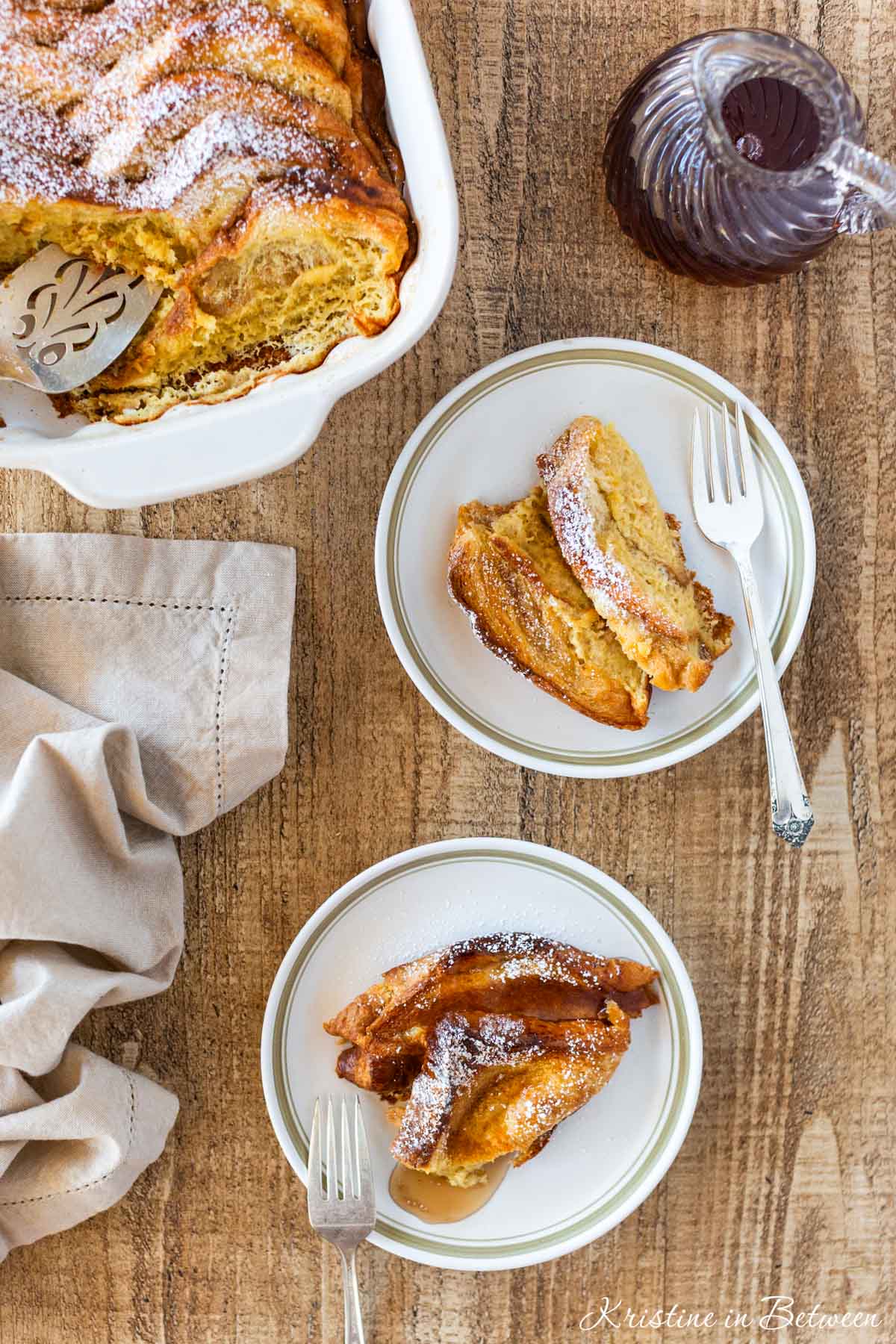 Two plates of French toast casserole with the pan in the background.