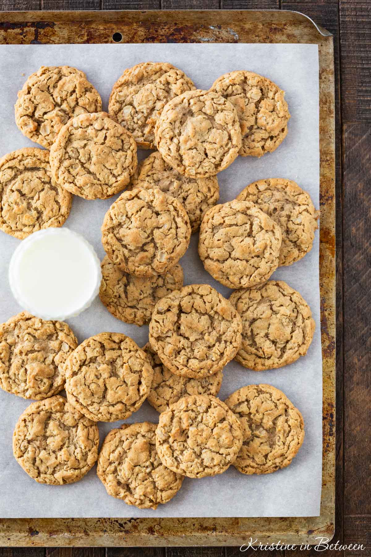 Chewy peanut butter oatmeal cookies on a baking sheet with a glass of milk.