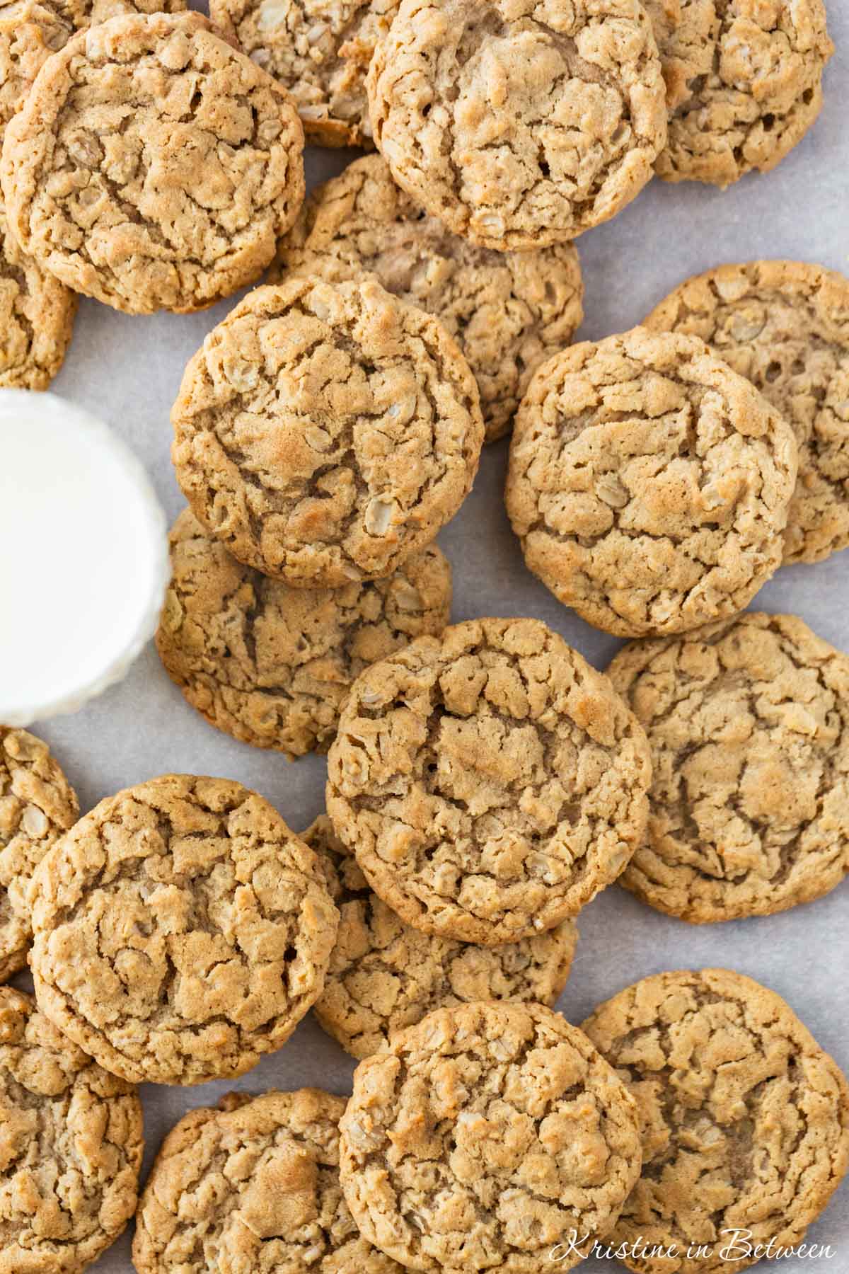 Chewy peanut butter oatmeal cookies on a baking sheet with a glass of milk.