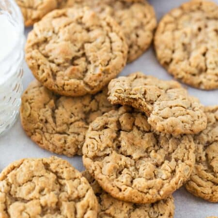 Chewy peanut butter oatmeal cookies on a baking sheet with a glass of milk.