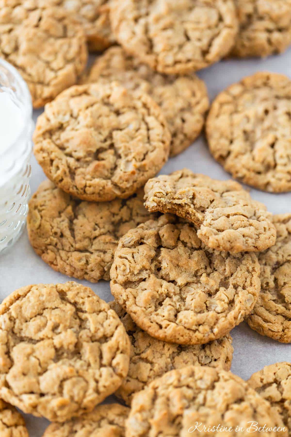 Chewy peanut butter oatmeal cookies on a baking sheet with a glass of milk.