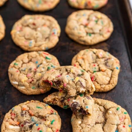 A whole batch of cookies laying on an old cookie sheet with a white napkin next to it.