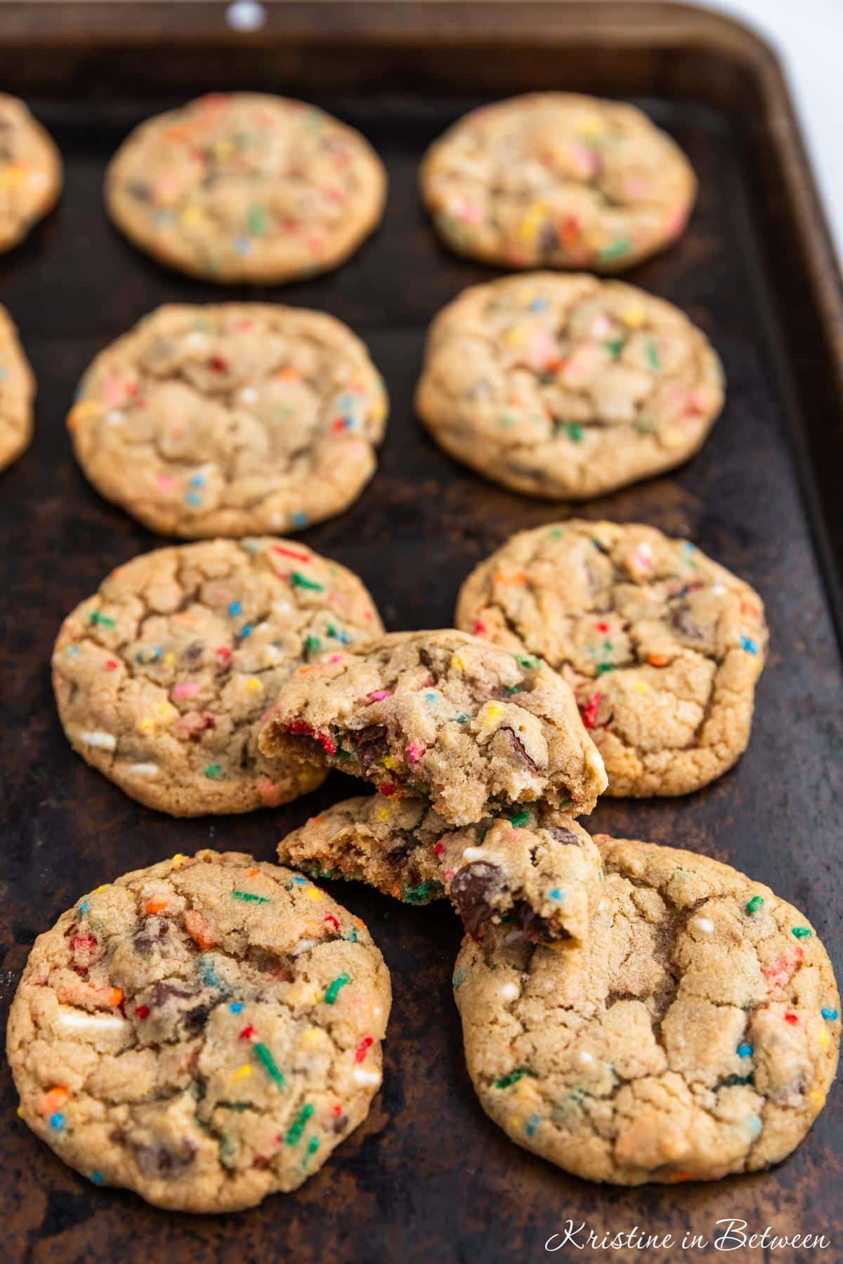 A whole batch of cookies laying on an old cookie sheet with a white napkin next to it.