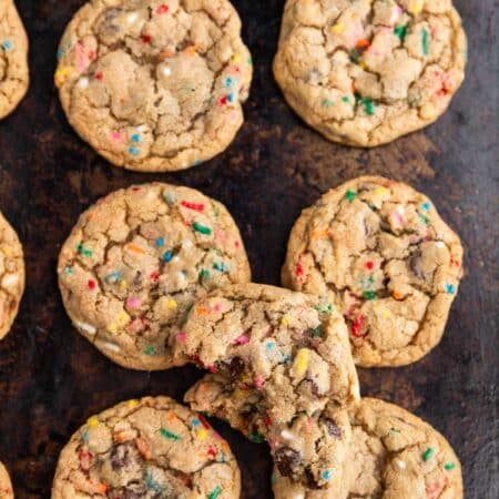 A whole batch of cookies laying on an old cookie sheet with a white napkin next to it.