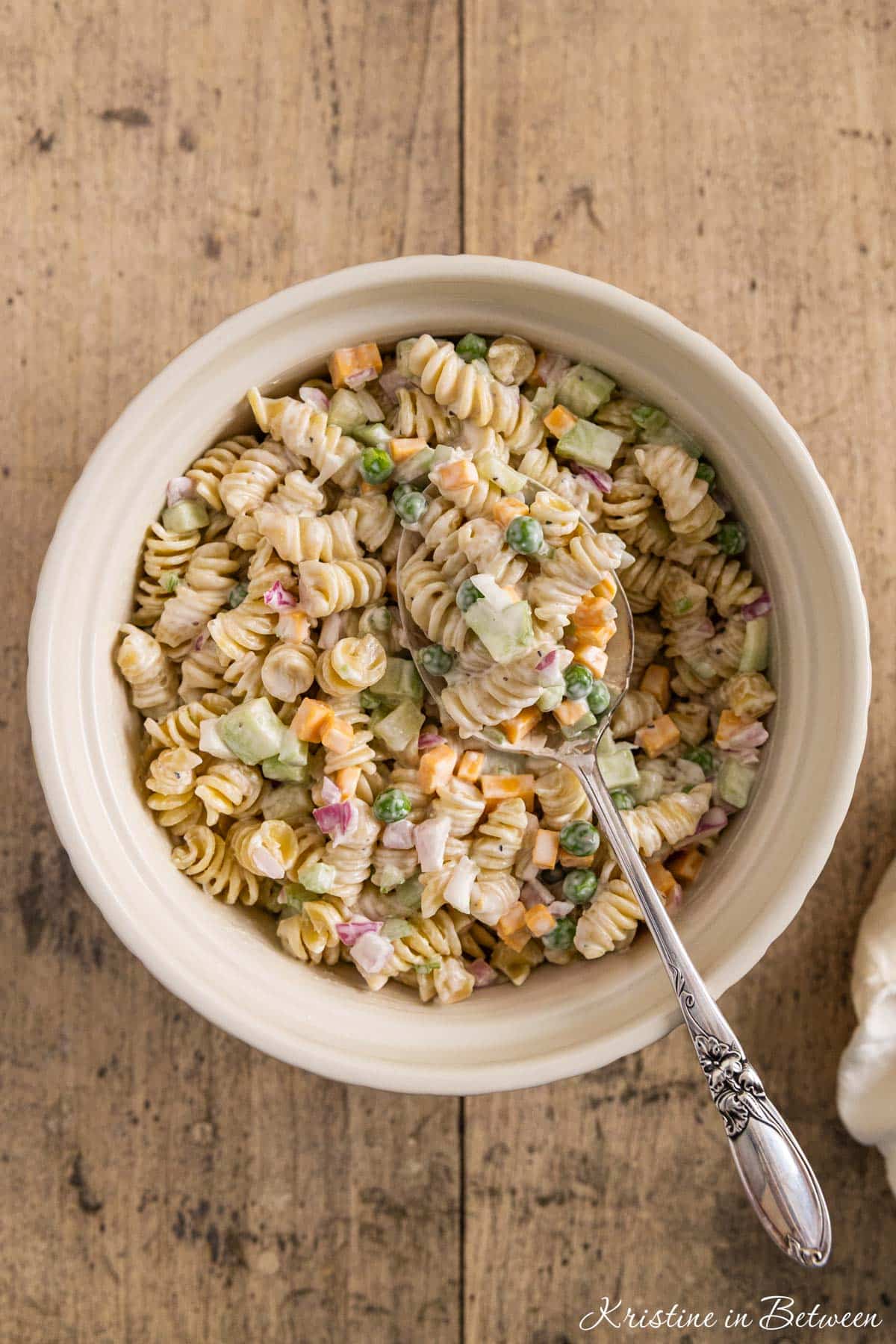 Creamy pasta salad in a bowl with a spoon on top, ready to eat.