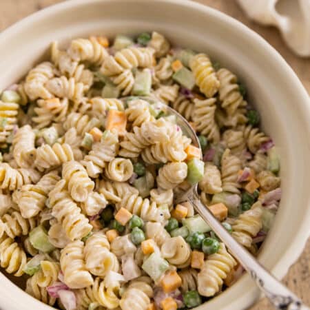 Creamy pasta salad in a bowl with a spoon on top, ready to eat.