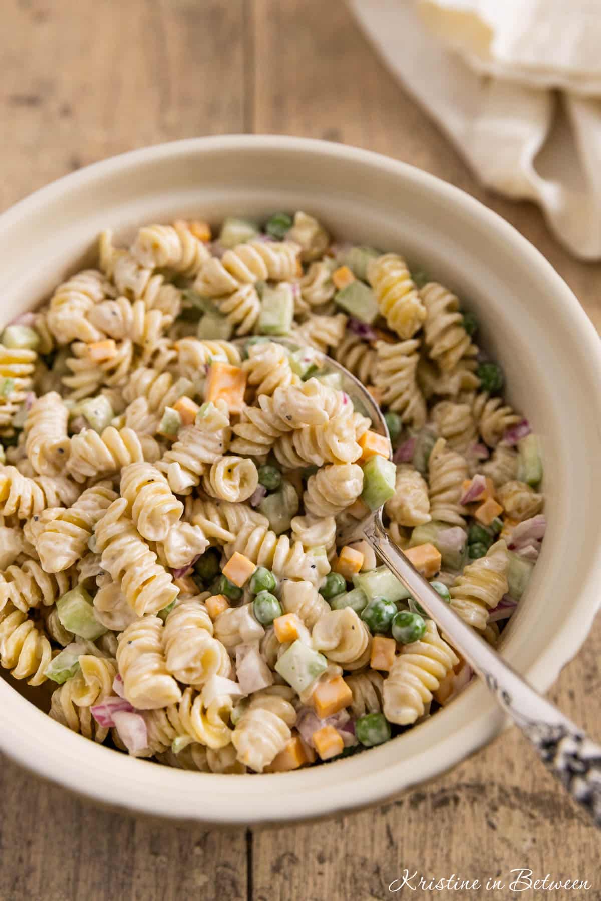 Creamy pasta salad in a bowl with a spoon on top, ready to eat.