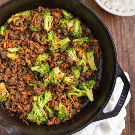 Ground beef teriyaki with broccoli and carrots in a cast iron skillet with an antique spoon.