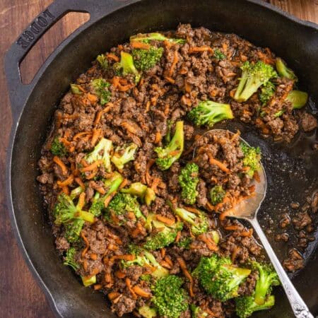 Ground beef teriyaki with broccoli and carrots in a cast iron skillet with an antique spoon.