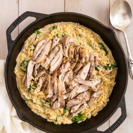 Lemon chicken orzo in a cast iron skillet with a spoon next to it.