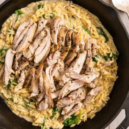 Lemon chicken orzo in a cast iron skillet with a spoon next to it.