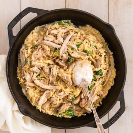Lemon chicken orzo in a cast iron skillet with a spoon in it, ready to serve.
