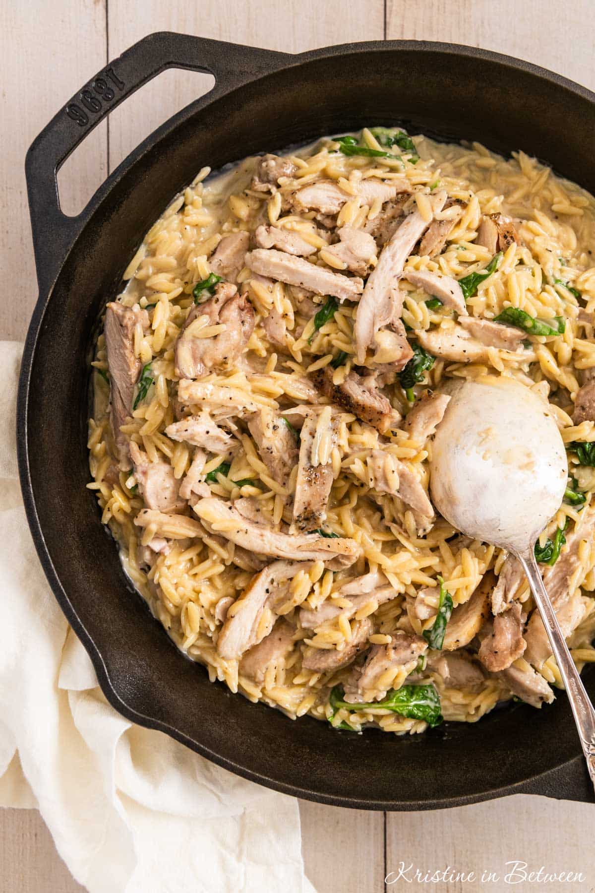 Lemon chicken orzo in a cast iron skillet with a spoon in it, ready to serve.