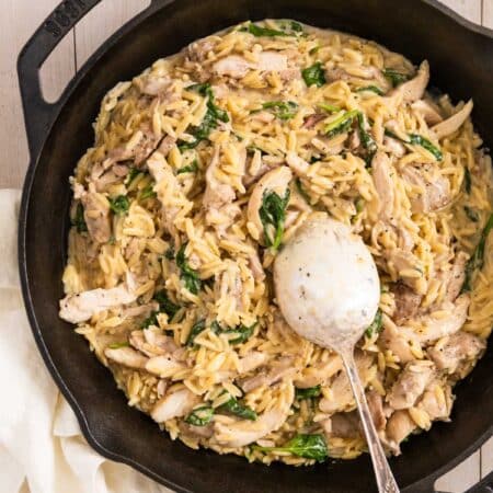 Lemon chicken orzo in a cast iron skillet with a spoon in it, ready to serve.