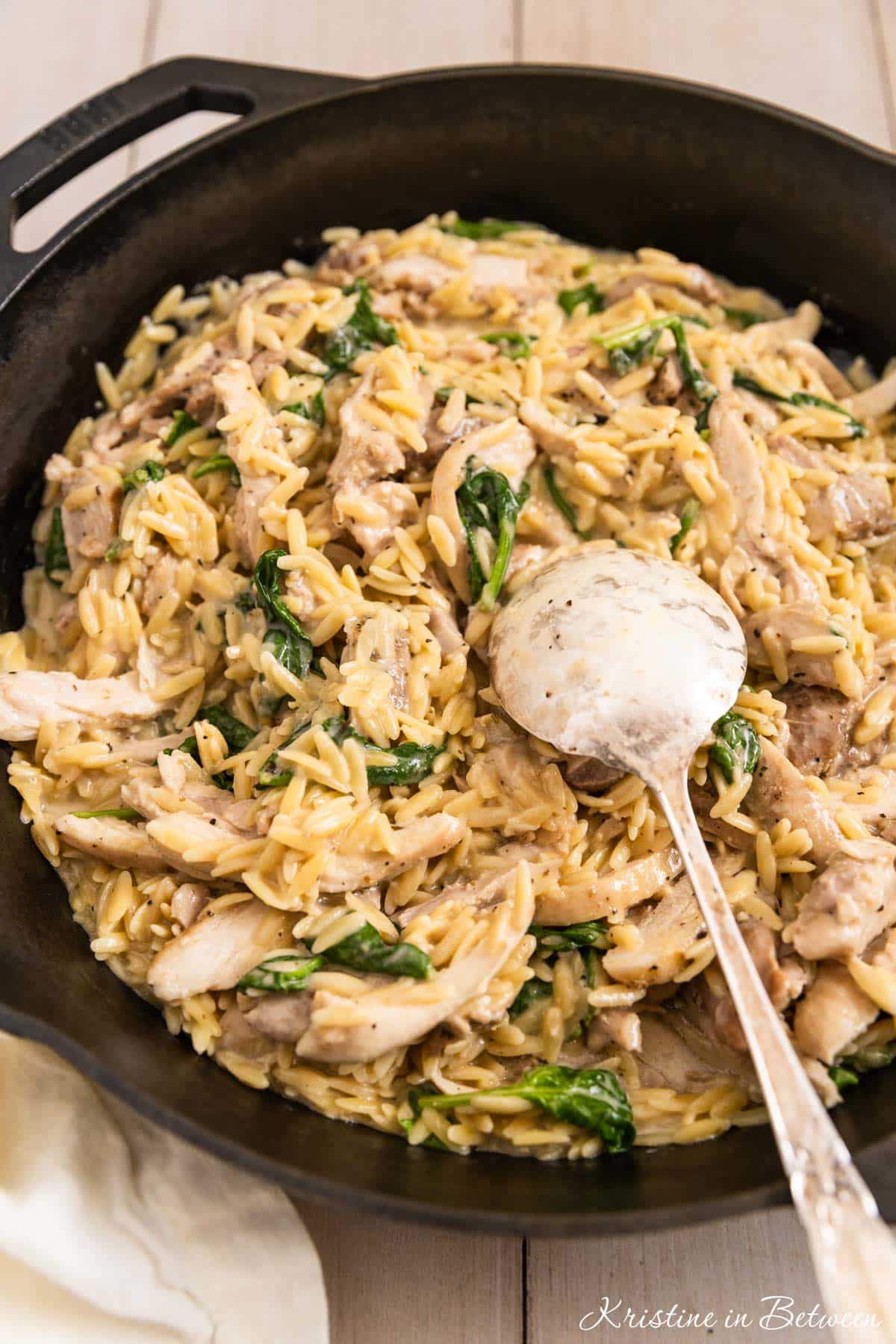 Lemon chicken orzo in a cast iron skillet with a spoon in it, ready to serve.