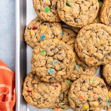 A whole tray of monster cookies sitting with an orange napkin.