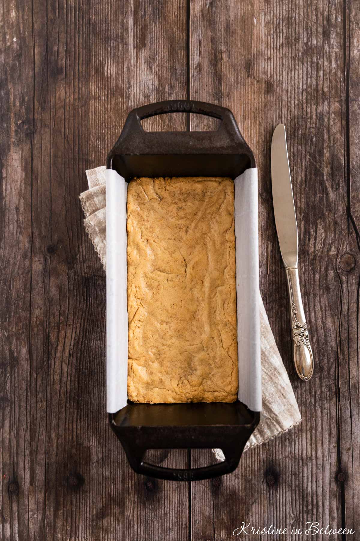 Blondies in a cast iron loaf pan with a knife next to them.
