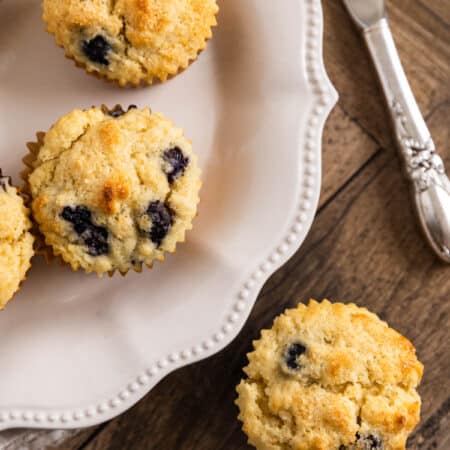 Small-batch blueberry lemon muffins on a white plate with a knife.