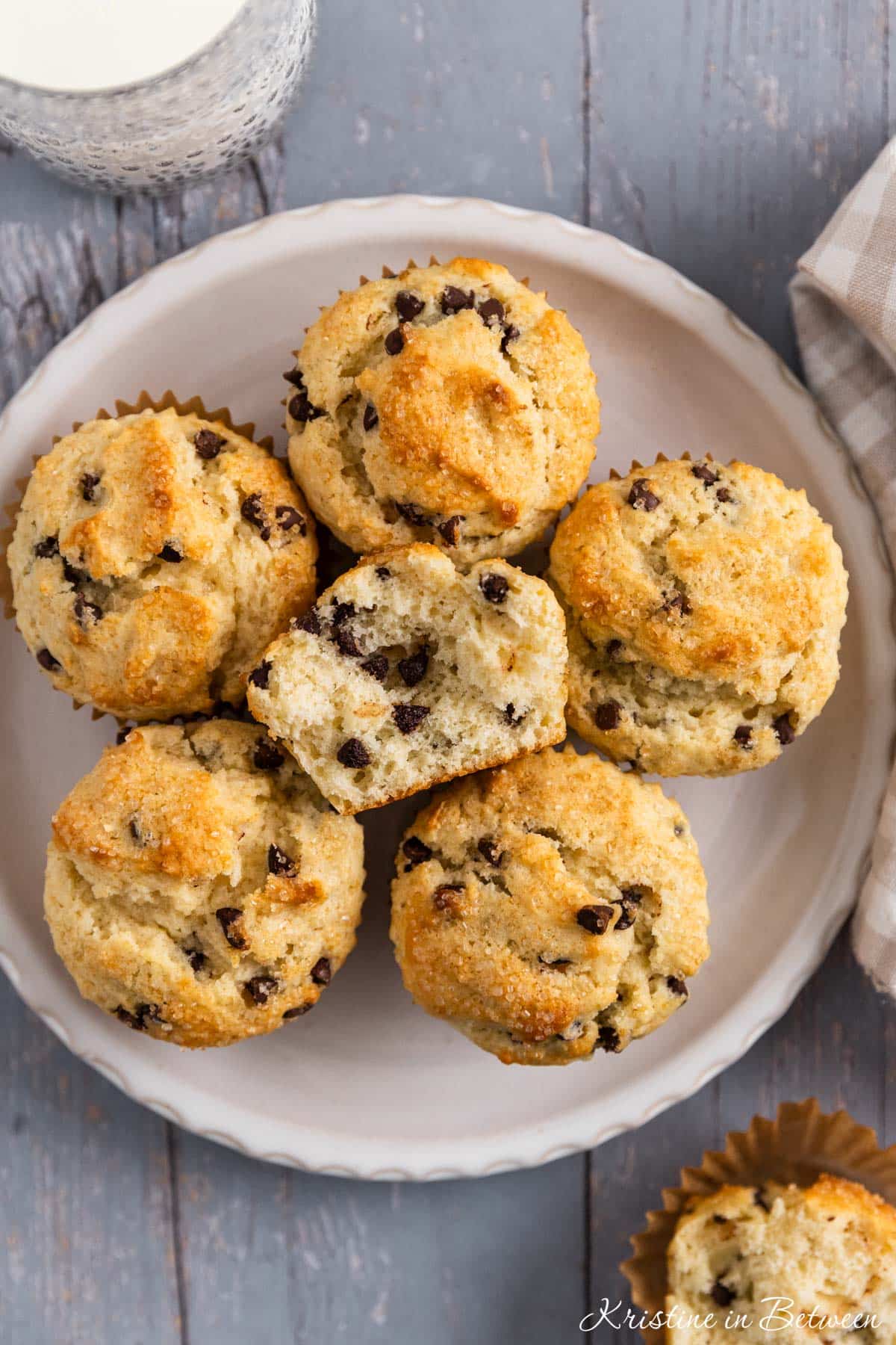 A plate of chocolate chip muffins with one cut in half to show the fluffy inside.