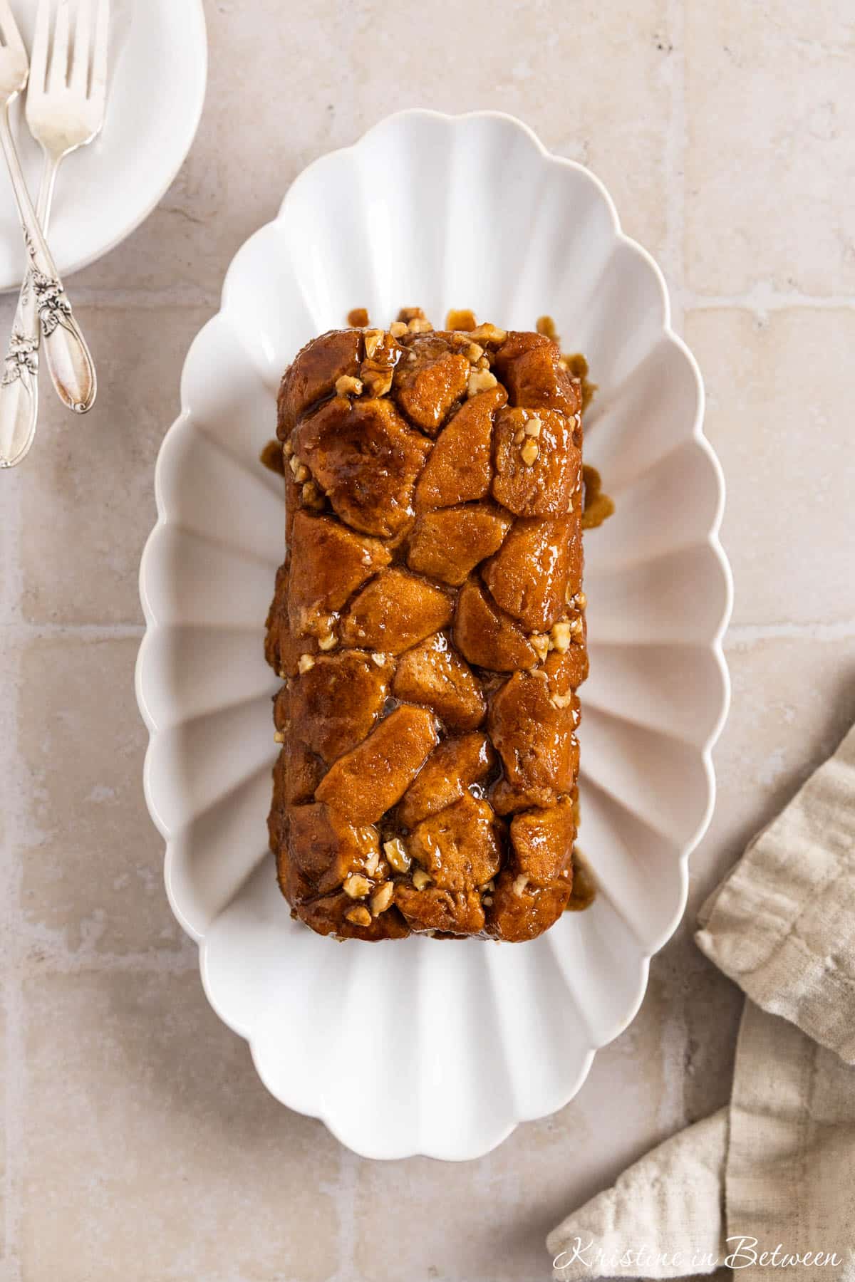A loaf pan monkey bread on a white scalloped plate with a napkin next to it.