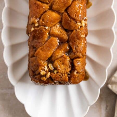 A loaf pan monkey bread on a white scalloped plate with a napkin next to it.