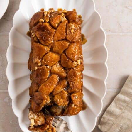 Monkey bread on a white plate with a bite on a fork and a napkin next to it.