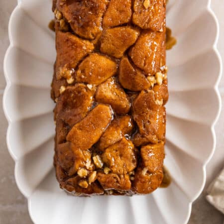 A loaf pan monkey bread on a white scalloped plate with a napkin next to it.