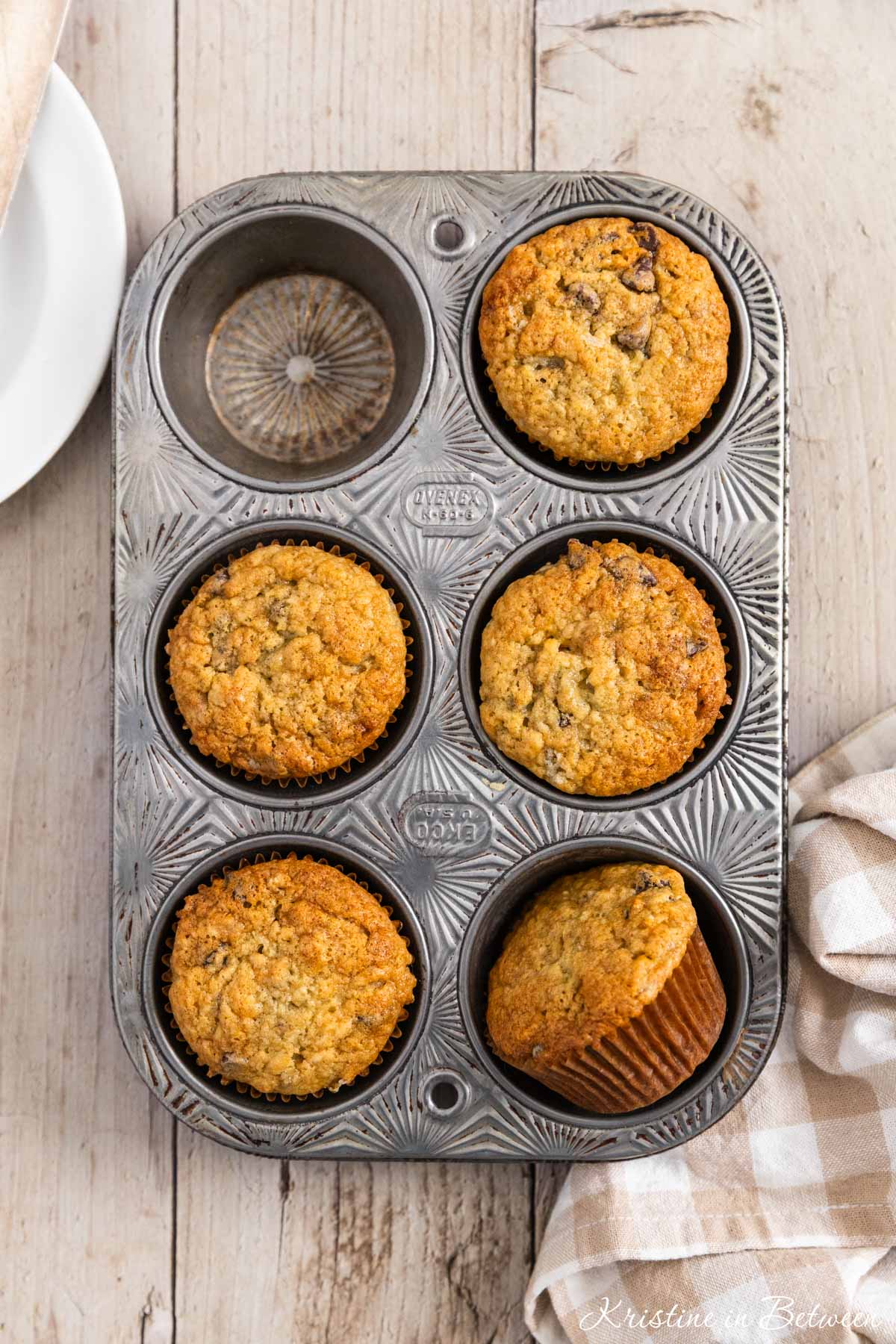 Chocolate chip banana bread muffins in a muffin tin with one missing.