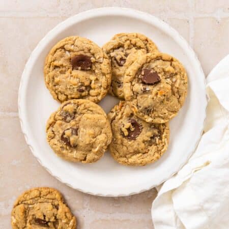 A plate of chocolate chip coconut cookies with a white napkin laying next to them.