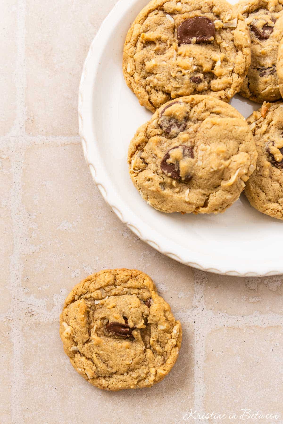 A plate of chocolate chip coconut cookies with a white napkin laying next to them.