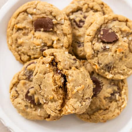 A plate of chocolate chip coconut cookies with a white napkin laying next to them.