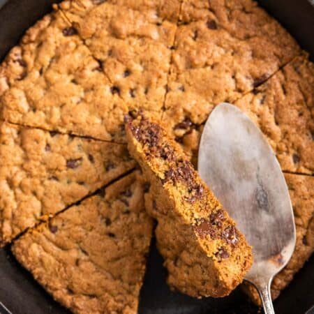 A skillet cookie in a cast iron pan with an antique spatula sitting on top.