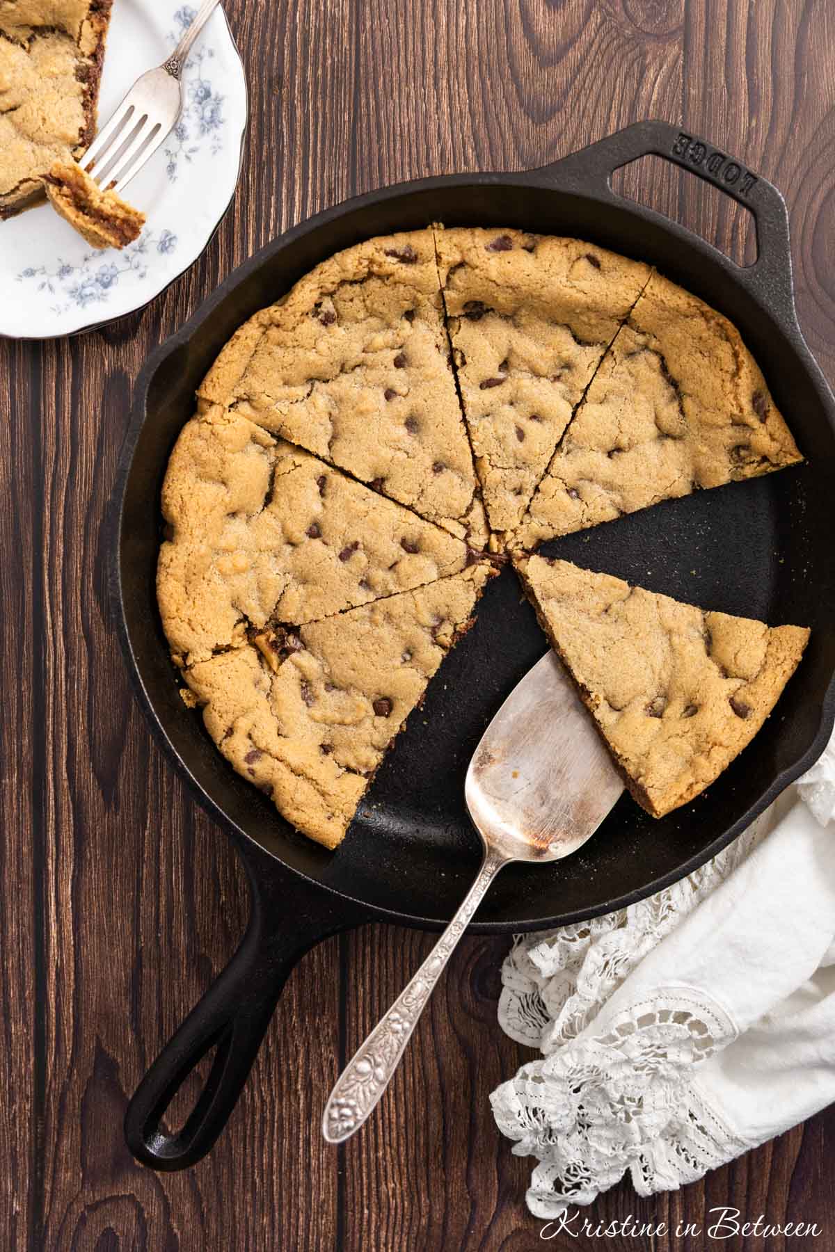 A skillet cookie sliced up with a piece on a spatula ready to be served.