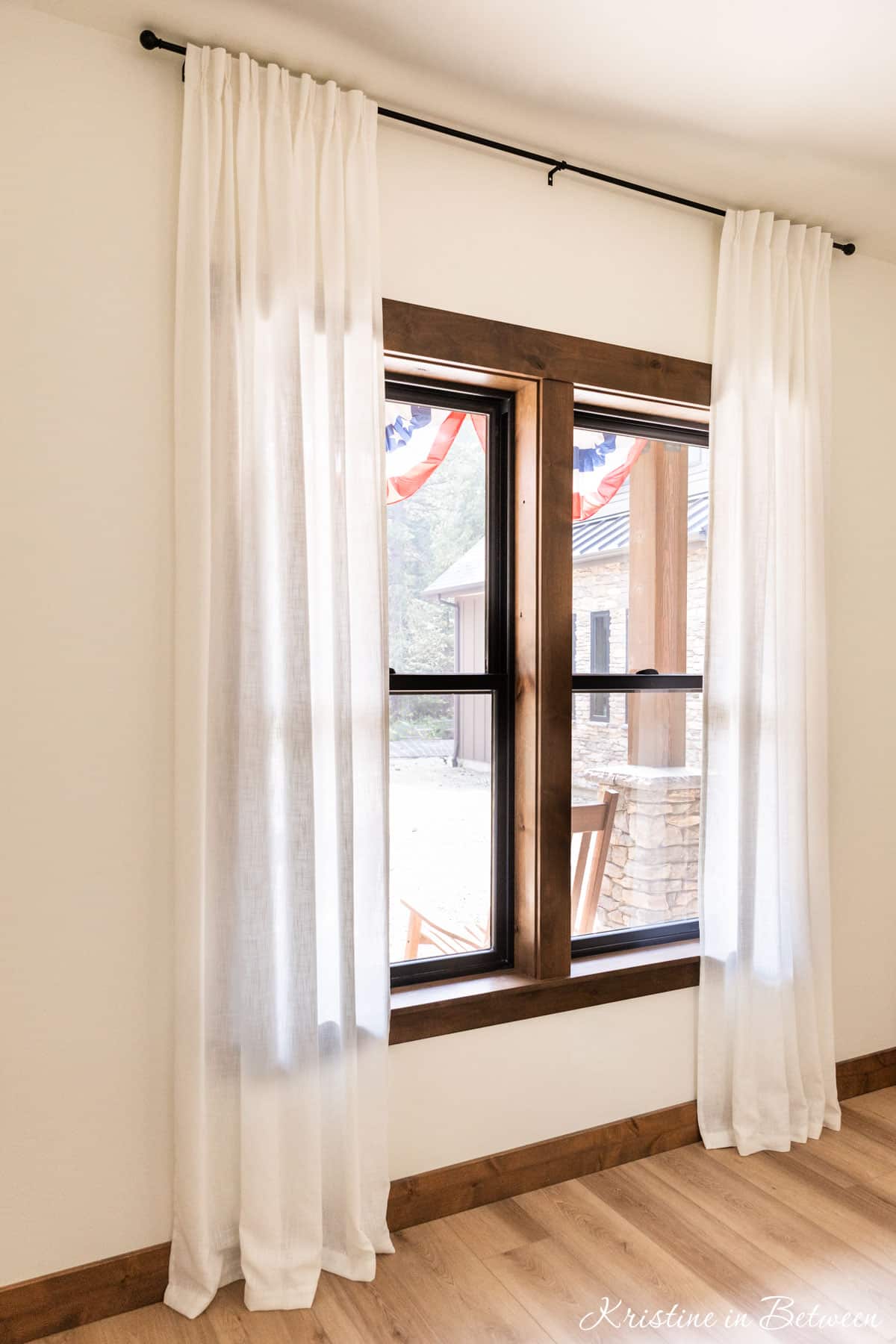 Full length curtains over a wood trimmed window, softly sitting on the floor.