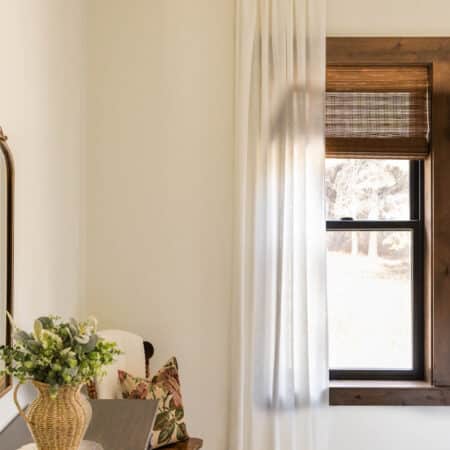 A white linen curtain hanging over an open window with a dresser off to the side.