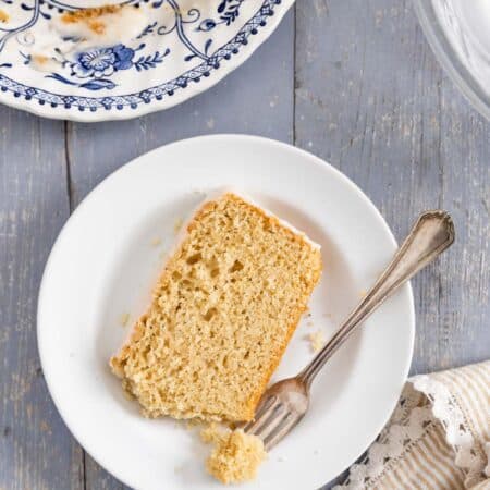A loaf of donut bread on a platter with frosting on top and a knife sitting next to it.