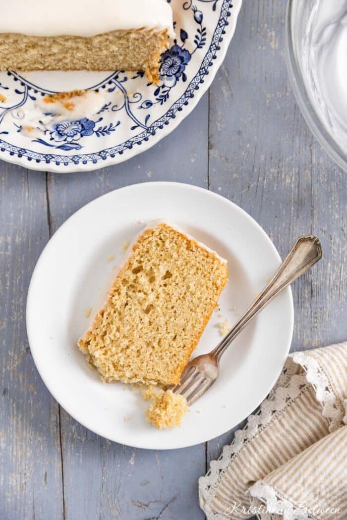 A loaf of donut bread on a platter with frosting on top and a knife sitting next to it.