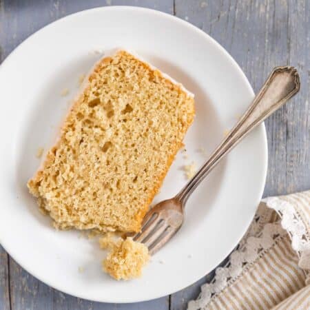 A slice of donut bread on a white plate with a bite on a fork.
