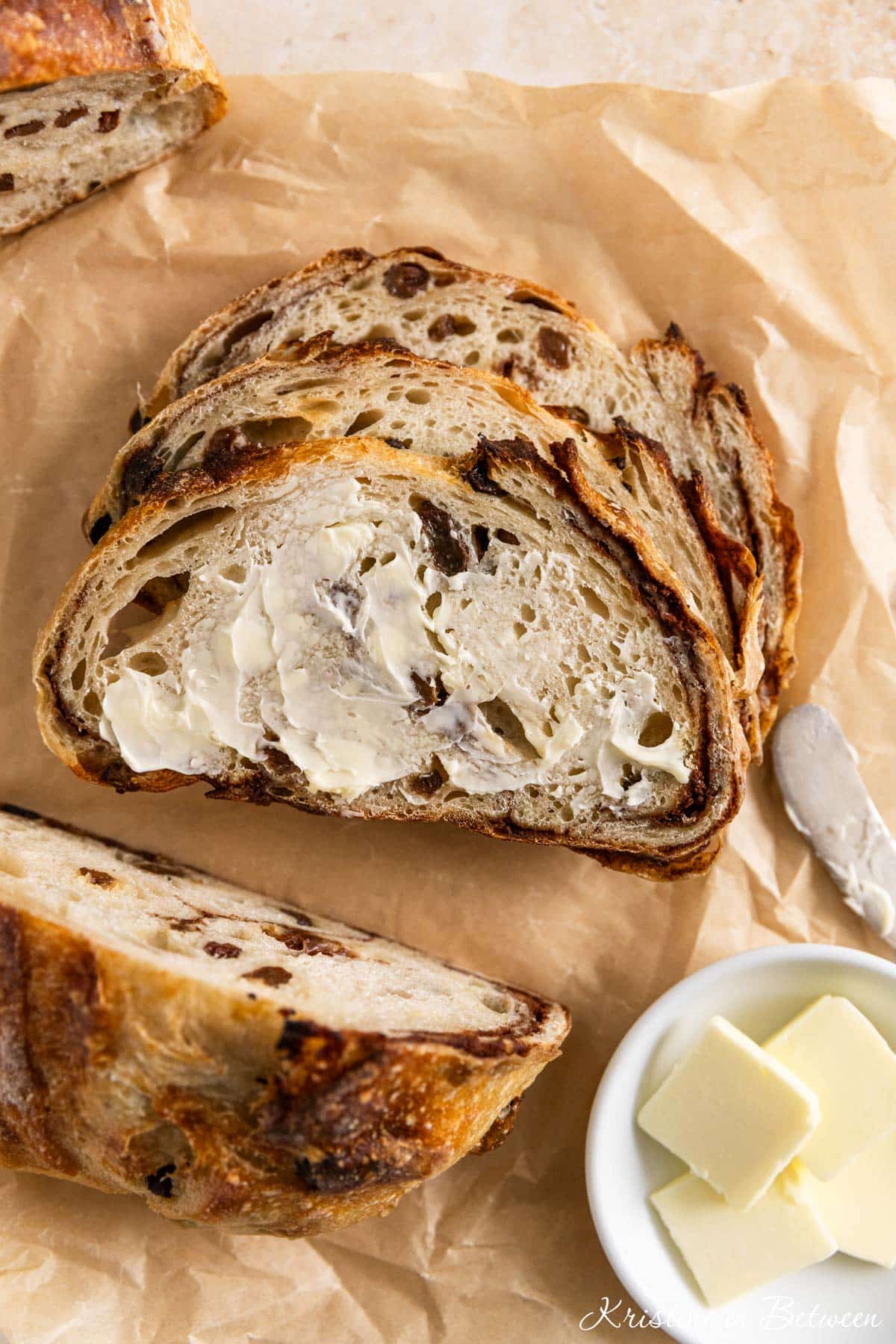 A slice of cinnamon raisin sourdough bread with butter on it.